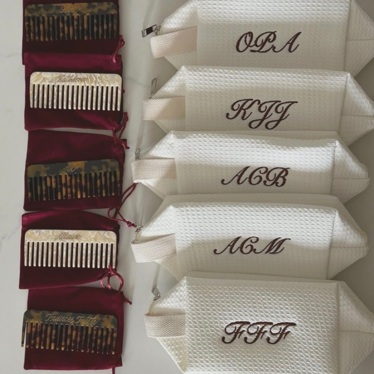 Six personalized white textured zippered pouches with embroidered monograms are displayed next to six matching hair combs in tortoiseshell and white, each with a burgundy velvet drawstring pouch.