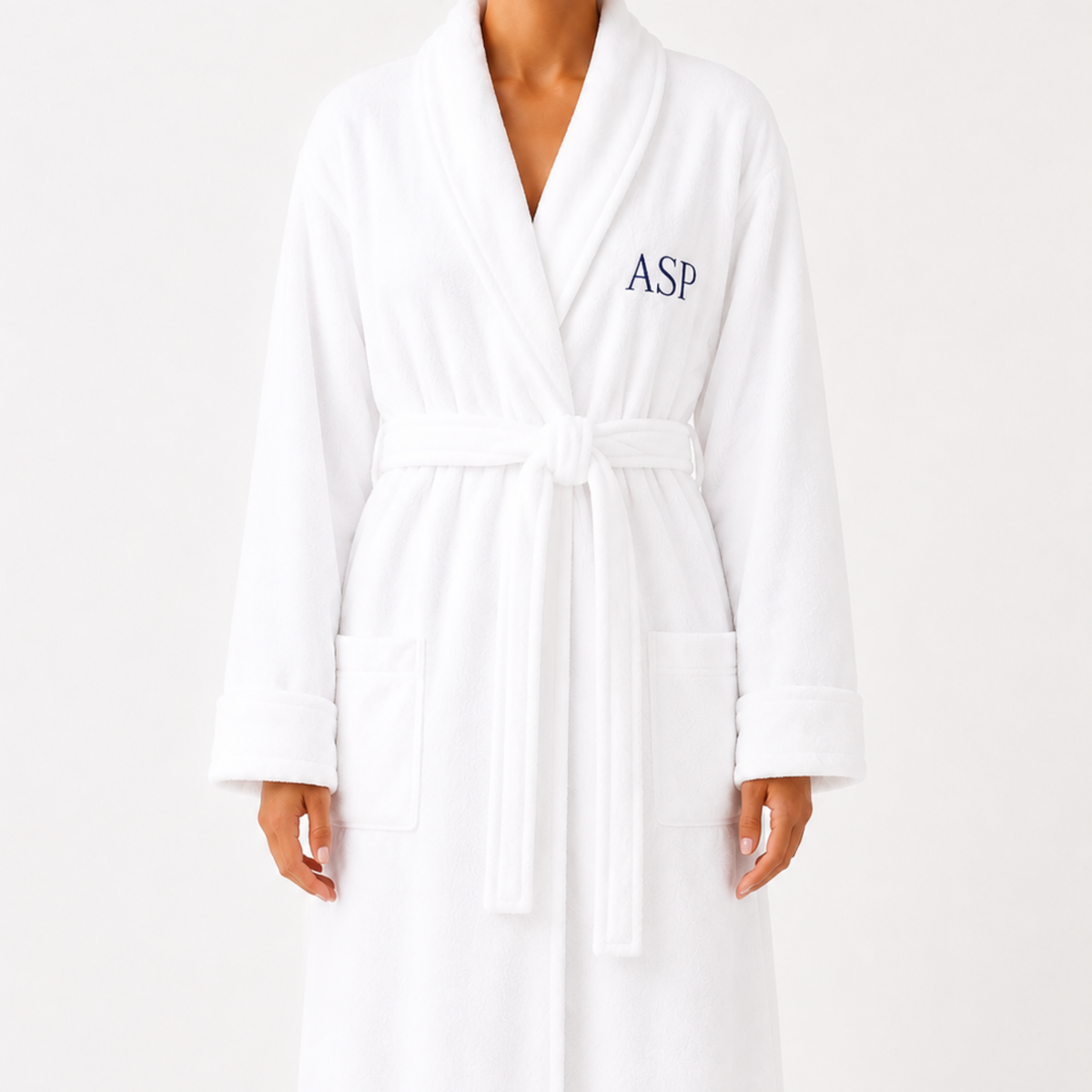 A white bathrobe with a tie belt and front pockets, featuring the navy embroidered letters 'ASP' on the left chest, shown on a model against a plain white background.
