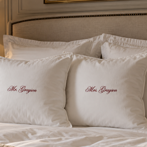Two white personalized bed pillows with embroidered names 'Mr. Grayson' and 'Mrs.