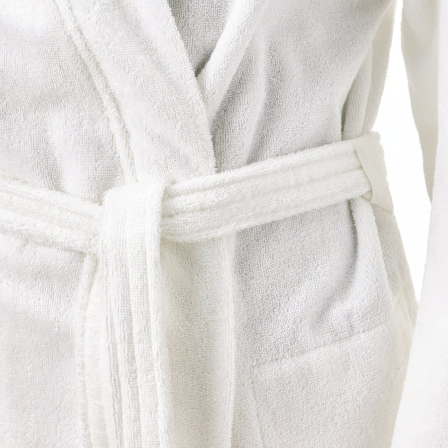 A close-up of a white terry cloth bathrobe with a matching belt, showing the soft textured fabric and wrap-style collar.